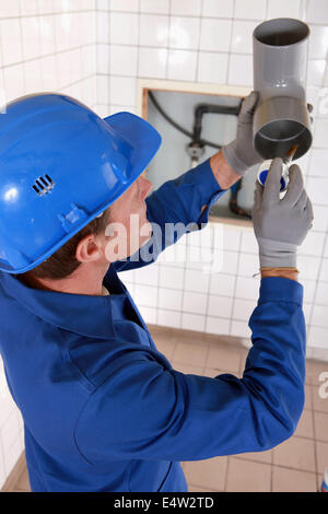 Plumber gluing grey water pipes Stock Photo