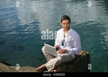 handsome man on the beach with his laptop Stock Photo