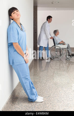 Tired nurse leaning against wall Stock Photo
