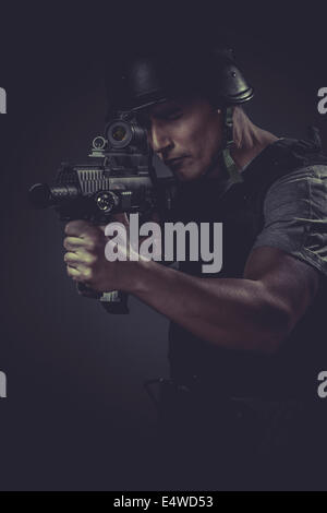 recreation player wearing protective helmet aiming pistol ,black armor and machine gun Stock Photo