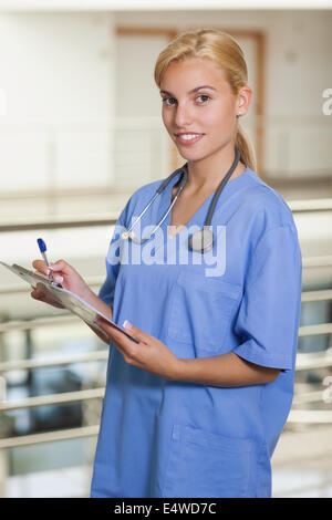Blonde nurse writing on a notepad on her desk in her office Stock Photo