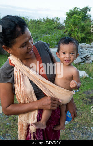 Bali, Indonesia.  Mother Carrying Son in a Shoulder Sling. Stock Photo
