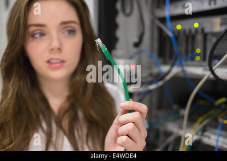 Woman looking confused at wire of server Stock Photo