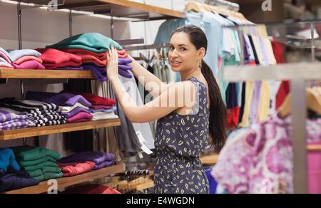 Woman putting jumpers on shelf Stock Photo