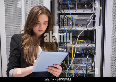 Woman using tablet pc in front of servers Stock Photo