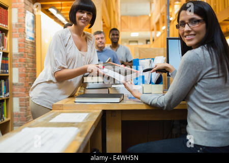 Librarian scanning book and handing to woman Stock Photo