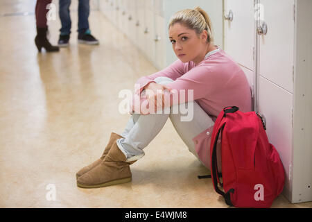 Student sitting against lockers Stock Photo