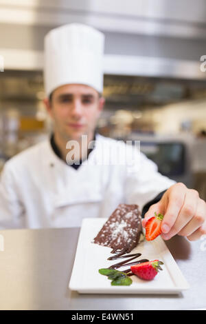Chef putting a strawberry on dessert plate Stock Photo