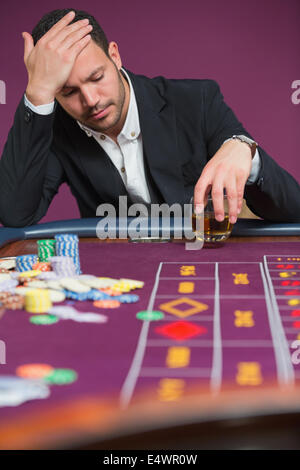 Man looking dejected at roulette table Stock Photo