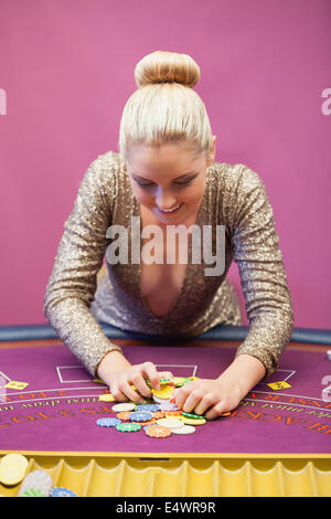 Woman in a casino grabbing chips Stock Photo