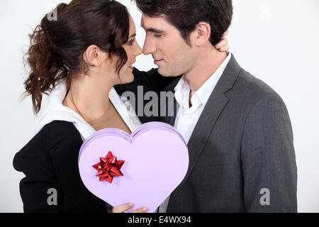 Couple holding heart-shaped box of chocolates Stock Photo