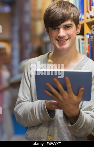 Man with tablet pc beside bookshelf Stock Photo