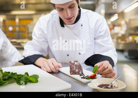 Chef putting mint leaf with his dessert Stock Photo