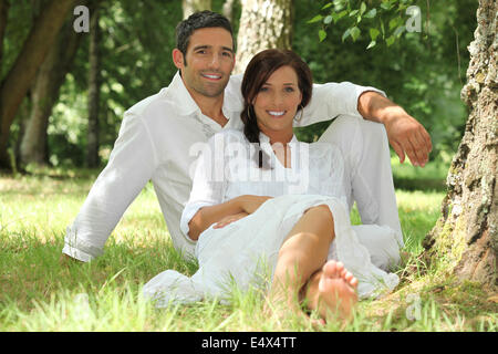 Couple in white sitting on the grass Stock Photo