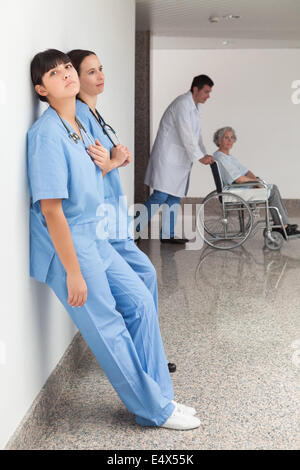 Two nurses leaning on wall Stock Photo