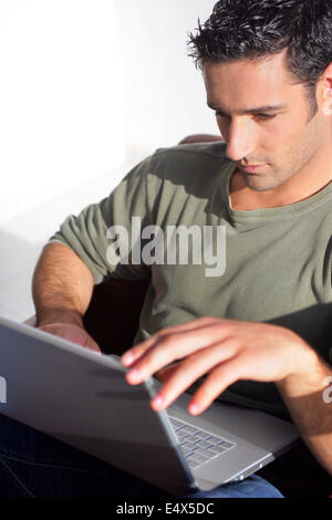 Dark haired man sat with laptop Stock Photo