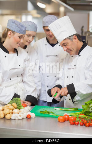 Chef teaching trainees how to cut vegetables Stock Photo