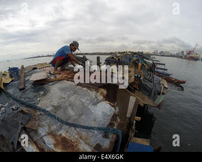 Manila, Philippines. 17th July, 2014. A man repairs the roof of his home after it was damaged by typhoon Rammasun at a slum area in Manila, the Philippines, on July 17, 2014. The death toll from typhoon Rammasun rose to 38, the local disaster agency said Thursday. The National Disaster Risk Reduction and Management Council (NDRRMC) said the typhoon also left 10 people injured while eight others were declared missing. Credit:  Rouelle Umali/Xinhua/Alamy Live News Stock Photo