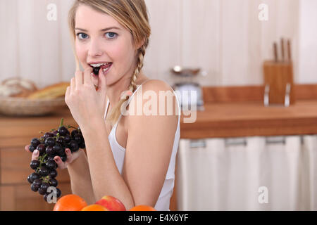 Blonde woman eating grapes Stock Photo