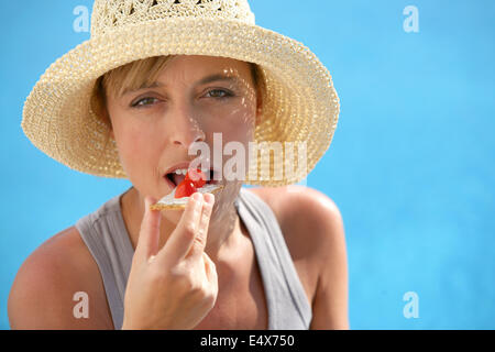 Woman in straw hat eating strawberry Stock Photo