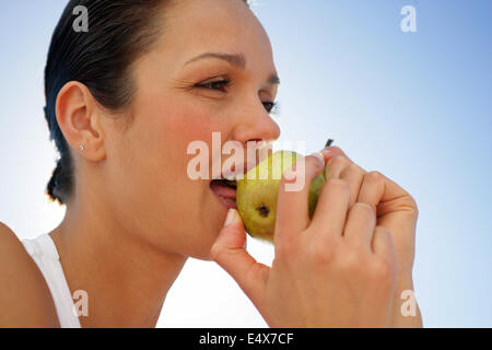 Woman biting into green apple Stock Photo