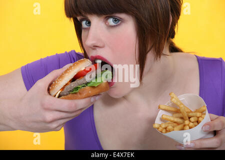 woman eating hamburger and French fries Stock Photo