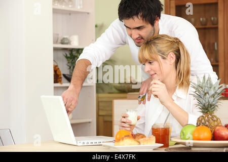 Couple eating breakfast in front of laptop Stock Photo