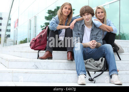 Three students sitting outside on some steps Stock Photo