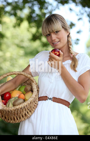 Blond woman carrying fruit basket Stock Photo