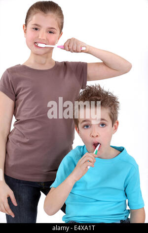 little boy and girl brushing their teeth Stock Photo