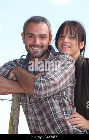 Farmer and wife stood outdoors by fence Stock Photo
