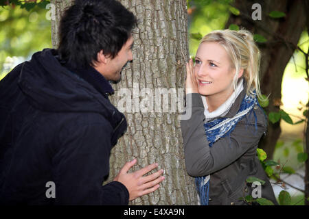 Couple hiding either side of tree Stock Photo