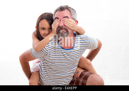 Caucasian father holding mixed race daughter, child covering dad's eyes Stock Photo