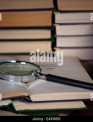 Magnifying glass on a pile of open books. Stock Photo