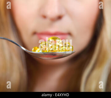 Woman holding a spoon full of pills Stock Photo