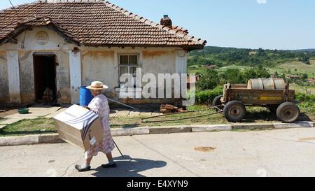 Golqm Dervent, Bulgaria. 17th July, 2014. Elderly Bulgarian woman walks past a house in the village Golqm Dervent as near by Bulgarian Borger police officers attend near newly build 30 kms long border fence at Bulgarian-Turkey border, as they present it to the press Thursday, July, 17, 2014. The wave of refugees flocking to Bulgaria has been growing again over the past few weeks. Bulgaria builded the fence on its border with Turkey to end illegal border crossings into the country. Credit:  ZUMA Press, Inc./Alamy Live News