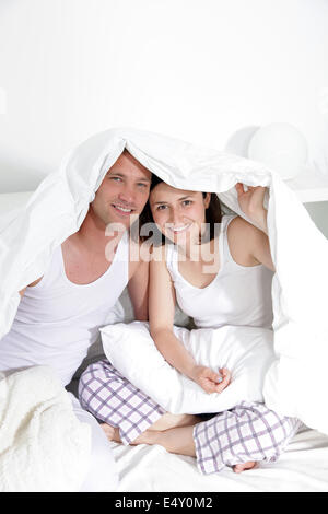 Young couple sitting under bedclothes Stock Photo
