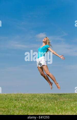 The happy young woman jumps in the field Stock Photo
