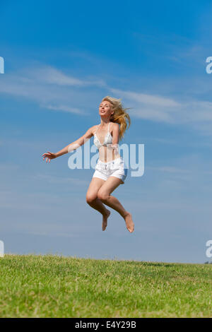 The happy young woman jumps in the field Stock Photo