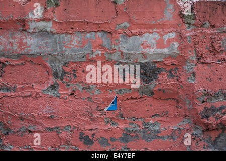 Old brick wall with remains of salmon pink red paint Stock Photo