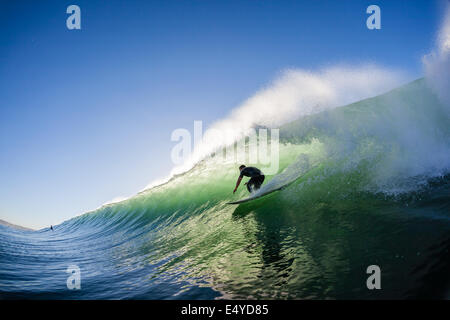 Surfer surfing  hollow crashing wave a swimming water photo closeup of action. Stock Photo