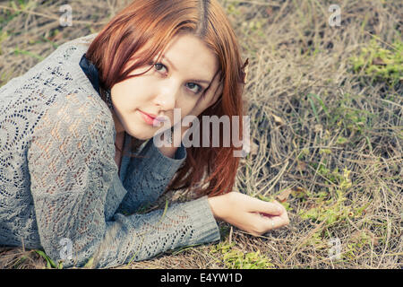 red haired women lying on autumn grass Stock Photo