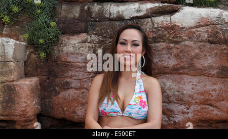 Young Asian woman in a bikini sunbathing on rocks Stock Photo