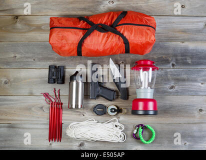 Overhead view of hiking gear and personal protection, pistol and knife, placed on rustic wood Stock Photo