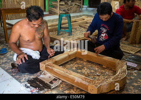Bali, Indonesia.  Woodcarvers Working on Window Frames in Workshop. Stock Photo