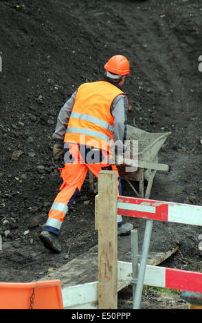Workers pushing wheelbarrow Stock Photo