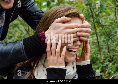 Hands Covering Woman's Eyes In Park Stock Photo