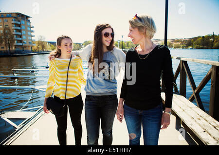 Two women and teenager (16-17 ) walking on footbridge Stock Photo