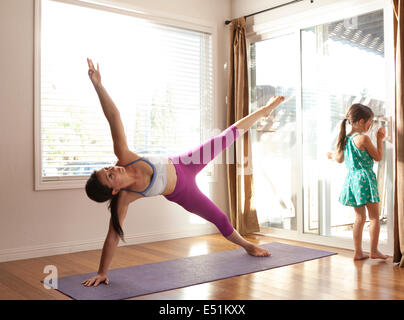 Mother and daughter doing yoga (6-7) at home Stock Photo