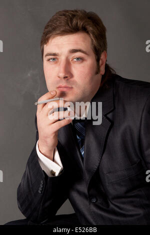 man in a business suit smoking a cigarette Stock Photo